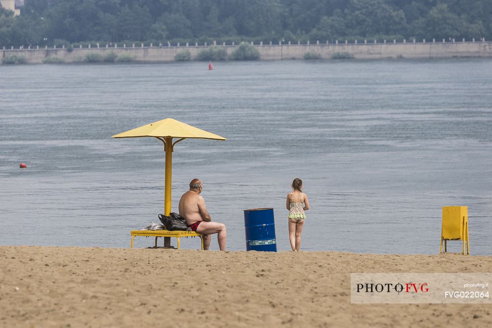 A man and a child relaxing on a siberian beach on the riverside of the river Ob in Novosibirsk, Russia