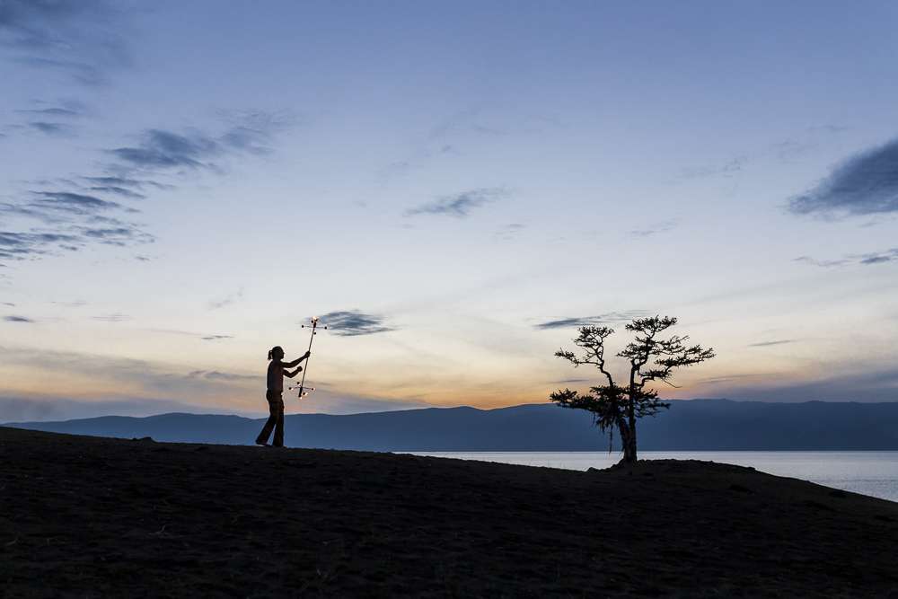 A boy dancing and playing with fire during the sunset at Olkhon Island, Bajkal lake, Russia