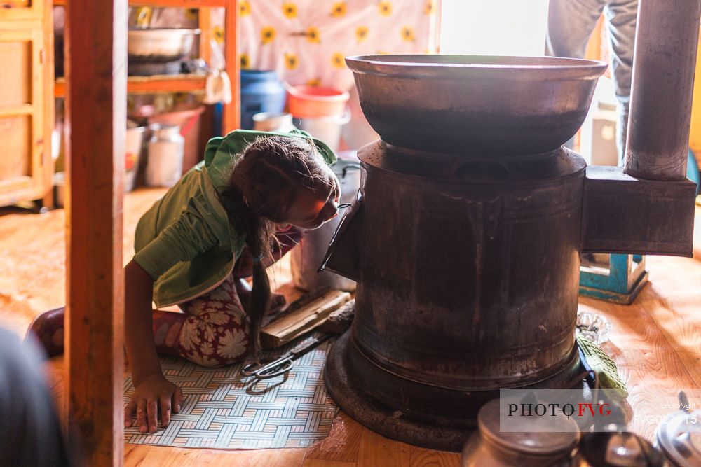 A young girl of a nomadic mongolian family lights the fire for the guests, Mongolia