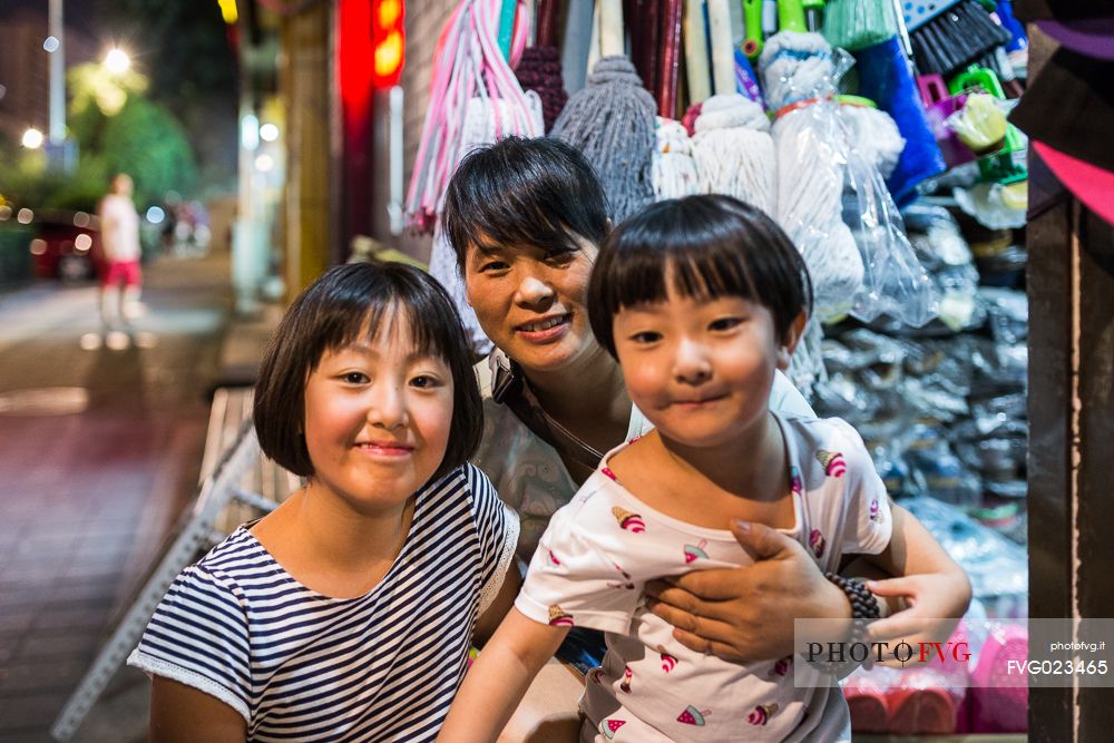 A woman and her daughters outside of her shop in the street in Beijing