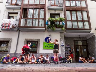 Some people in a row waiting for the tourist info point office opening in order to reserve their place at the local hostel