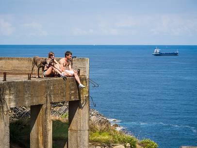 A young girl and a young boy sitting near the ocean with their dog