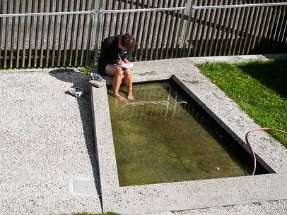 A pilgrim writing her daily diary with her feet inside cold water A pilgrim writing her daily diary with her feet inside cold water