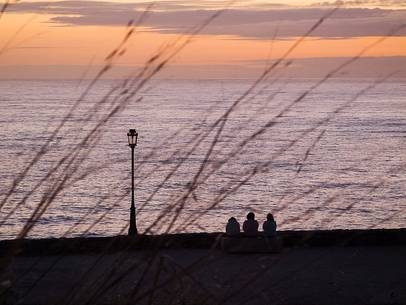 Three people admiring an amazing sunset in Muxa