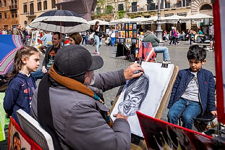 A street artist portrays a children in Piazza Navona.