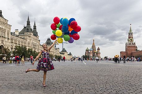 A young girl with some colored balloons posing for a photo in the Red Square in Moscow, Russia