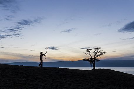 A boy dancing and playing with fire during the sunset at Olkhon Island, Bajkal lake, Russia