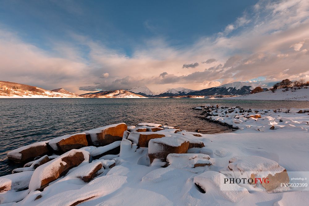 A clearing snowstorm reveal the peaks of the Gran Sasso mountain chain from Campotosto lake, Gran Sasso and Monti della Laga National Park, Abruzzo, Italy