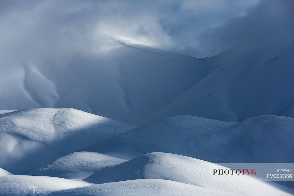 The light that penetrates draws particular shapes on the snowy ground along the road to Mount Prata, Sibillini National Park, Marches, Italy, Europe
