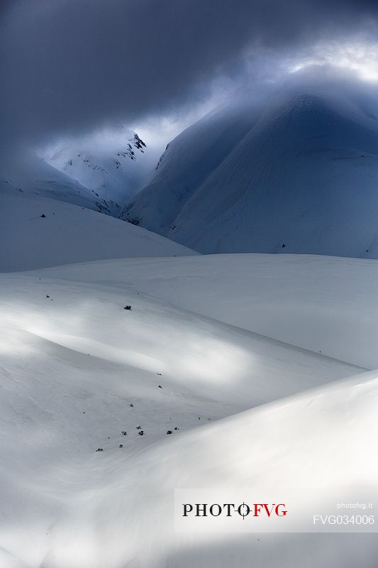 The light that penetrates draws particular shapes on the snowy ground along the road to Mount Prata, Sibillini National Park, Marches, Italy, Europe