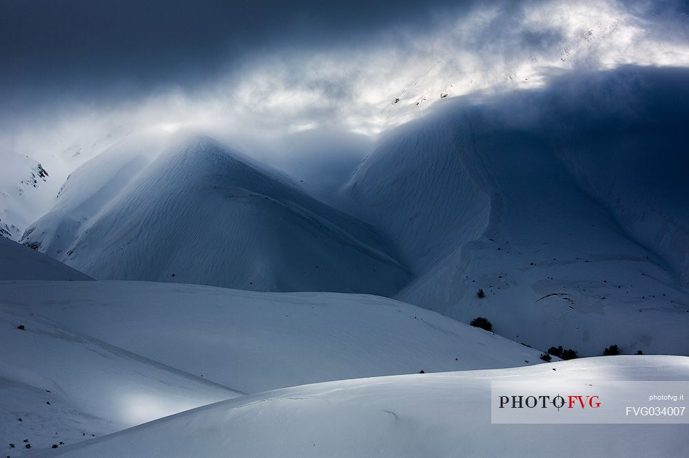 The light that penetrates draws particular shapes on the snowy ground along the road to Mount Prata, Sibillini National Park, Marches, Italy, Europe