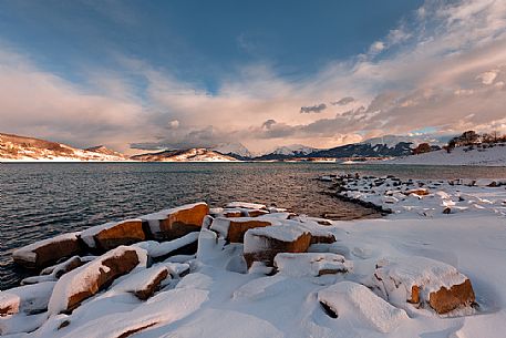 A clearing snowstorm reveal the peaks of the Gran Sasso mountain chain from Campotosto lake, Gran Sasso and Monti della Laga National Park, Abruzzo, Italy