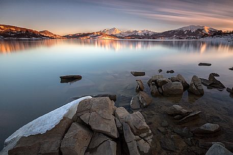 A tongue of ice to lap the shore of Campotosto lake at sunset, Gran Sasso and monti della Laga national park, Abruzzo, Italy