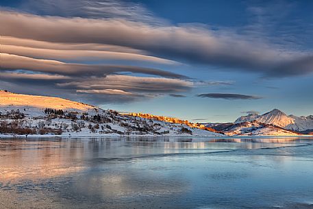 The clouds caress the lake of Campotosto and the light gives strength and character to the whole scene, Gran Sasso and monti della Laga national park, Abruzzo, Italy