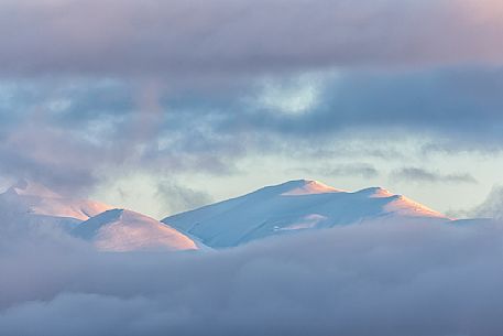 A clearing snowstorm reveal the peaks of the Gran Sasso mountain chain from Campotosto lake, Gran Sasso and Monti della Laga national park, Abruzzo, Italy