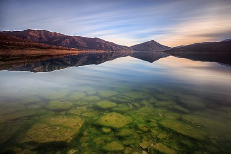 The clouds gently caress the lake of Campotosto, fleeing quickly towards new horizons, Gran Sasso e Monti della Laga national park, Abruzzo, Italy