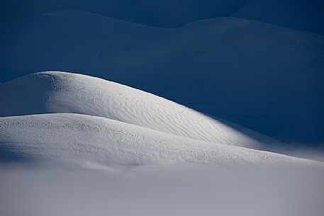 The light that penetrates draws particular shapes on the snowy ground along the road to Mount Prata, Sibillini National Park, Marches, Italy, Europe