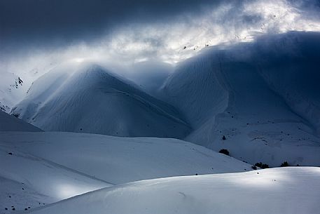 The light that penetrates draws particular shapes on the snowy ground along the road to Mount Prata, Sibillini National Park, Marches, Italy, Europe