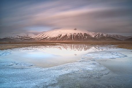 Snow melting in the Pian Grande of Castelluccio di Norcia, in the background the Vettore mountain at dawn, Sibillini National Park, Umbria, Italy, Europe