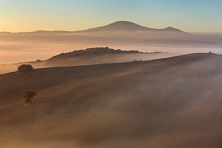 The beauty of the hills in Val d'Orcia in the fog at sunrise, Pienza, Orcia valley, Tuscany, Italy