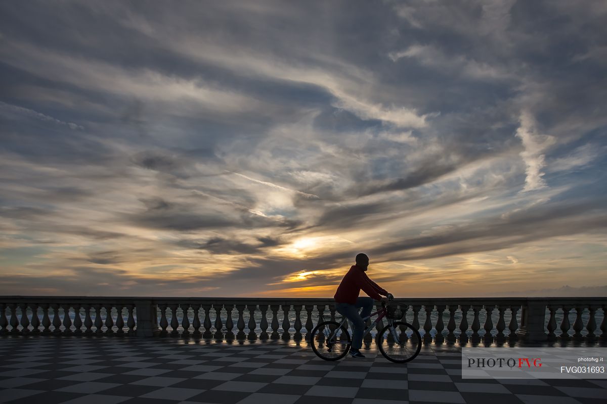 Cyclist rides on the Mascagni terrace at sunset, Livorno, Tuscany, Italy