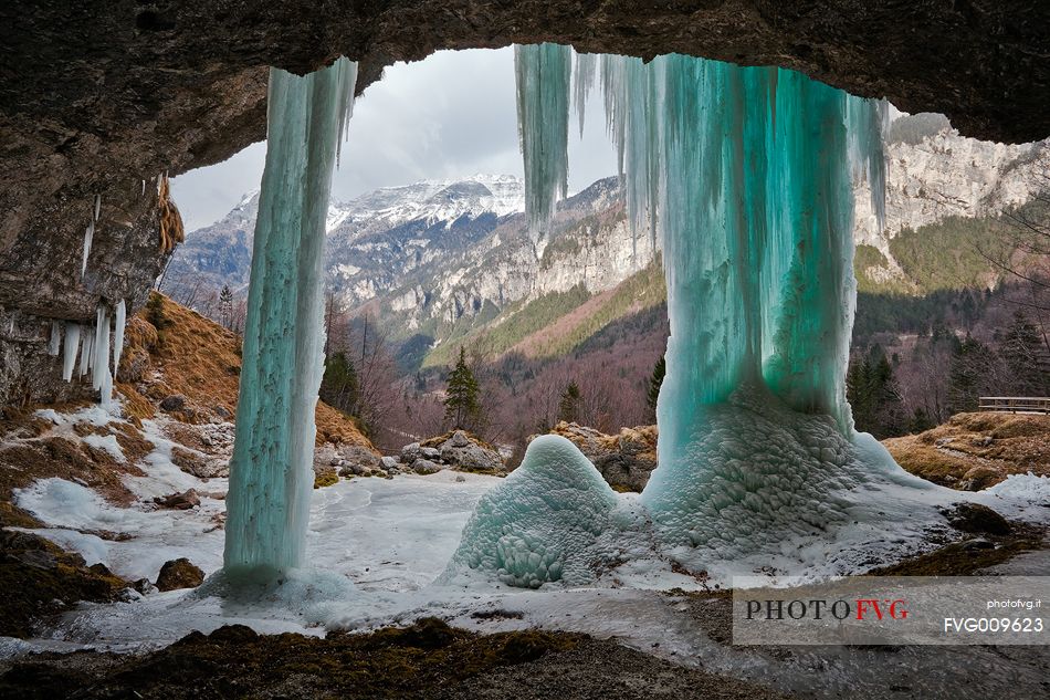 The frozen Goriuda Waterfall seen from behind, with the Julian Alps as a background.