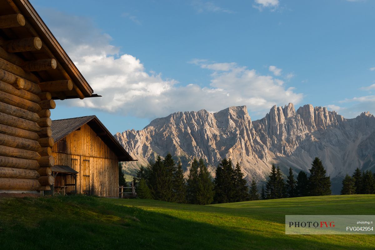 The  Latemar framed by a blu sky, a green meadow and a chalet made of wood, Carezza, dolomites, Trentino Alto Adige, Italy, Europe
