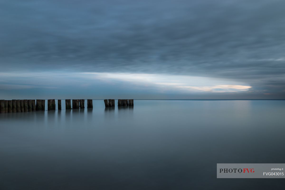 A wooden pile trail points towards the horizon between sky and sea, Bibione, Adriatic sea, Veneto, Italy, Europe