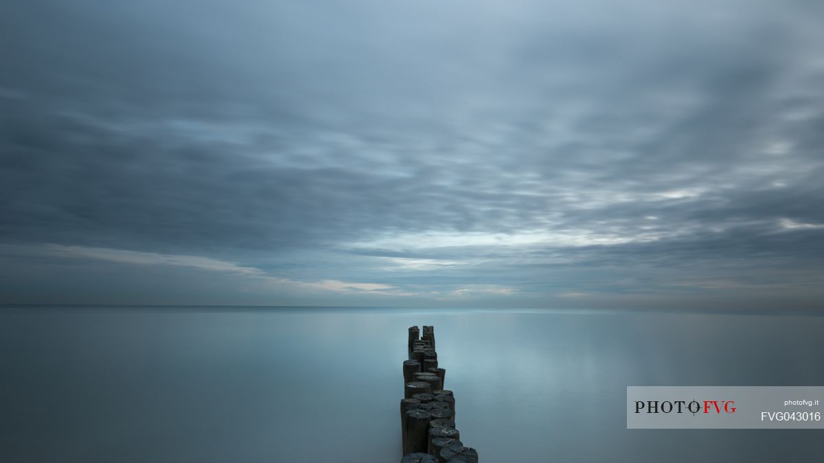 A wooden pile trail points towards the horizon between sky and sea, Bibione, Adriatic sea, Veneto, Italy, Europe