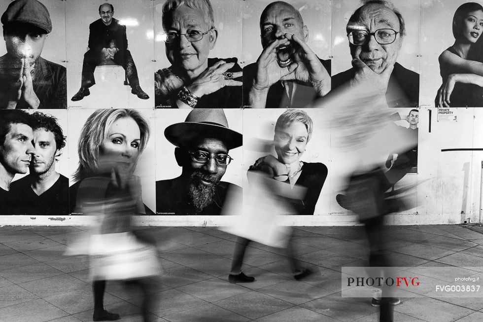 People walk in front of some billboards People walk in front of some billboards