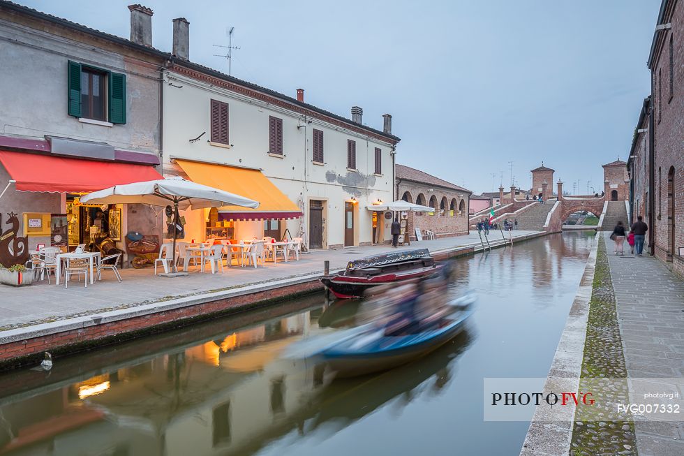 Evening view of Tre Ponti bridge with a tipical fisherman ship and a food shop Evening view of Tre Ponti bridge with a tipical fisherman ship and a food shop