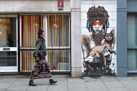A young woman walk in front of one murales in borough of Shoreditch