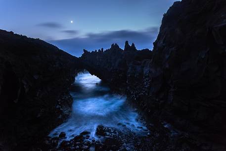 One lava arch over the sea in the moonlight