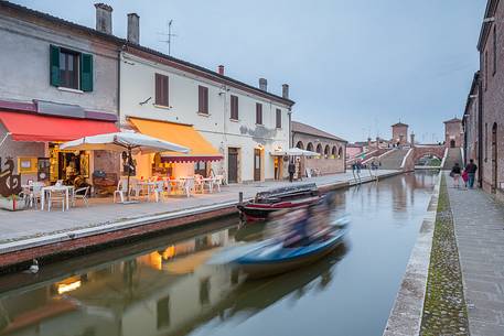 Evening view of Tre Ponti bridge with a tipical fisherman ship and a food shop Evening view of Tre Ponti bridge with a tipical fisherman ship and a food shop