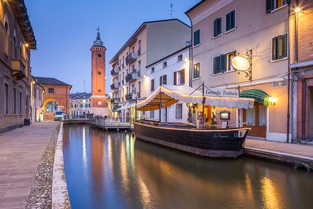 Evening view of the Torre dell'Orologio with a ship and a tipical restaurant near the Loggia del Grano palace