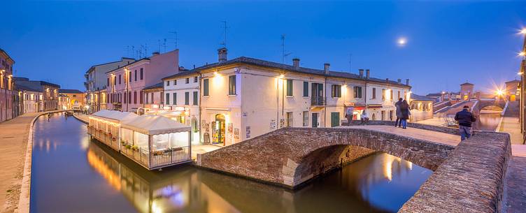 Evening view of small centre's rivers and Tre Ponti bridge in the moonlight Evening view of small centre's rivers and Tre Ponti bridge in the moonlight