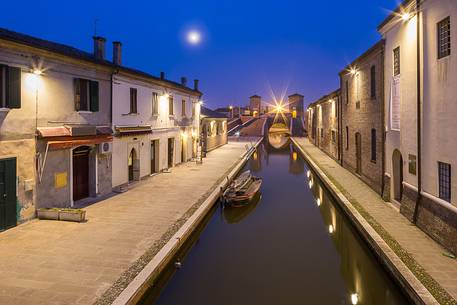 Evening view of a small centre's river and Tre Ponti bridge in the moonlight