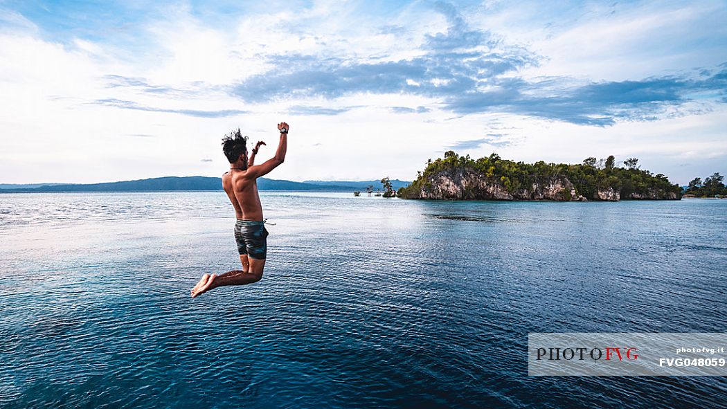 Local man dives in the wonderful sea of the Kri island, one of the Raja Ampat archipelago most popular tourist spots, West Papua, Indonesia