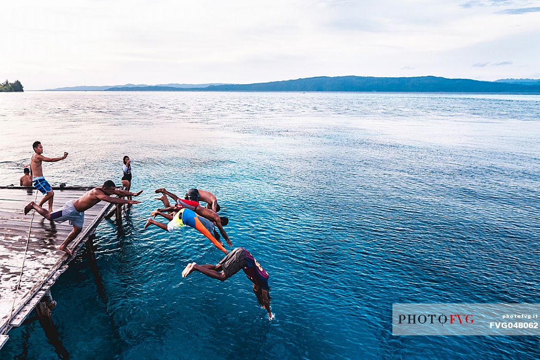 Group of people dives in the wonderful sea of the Kri island, one of the Raja Ampat archipelago most popular tourist spots, West Papua, Indonesia