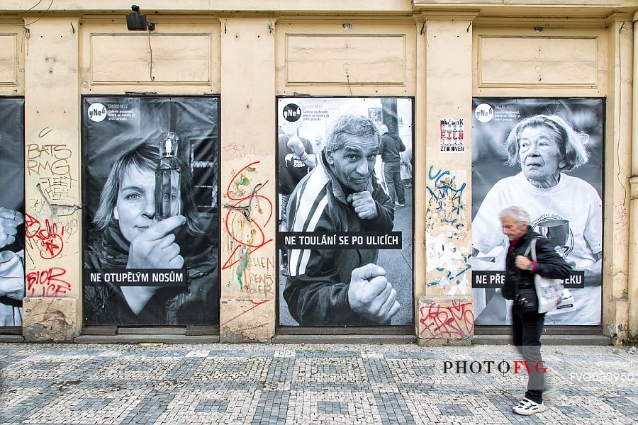 Old man walking in front of advertising pictures