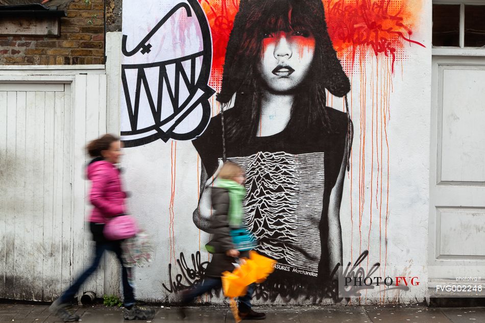 Young girls walking in front of a street art work of brasilian street artist Chivitz