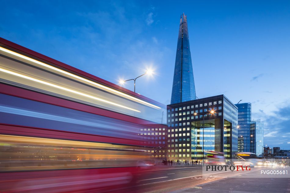 A view of The Shard from London Bridge at dusk with a tipycal London Double decker red bus