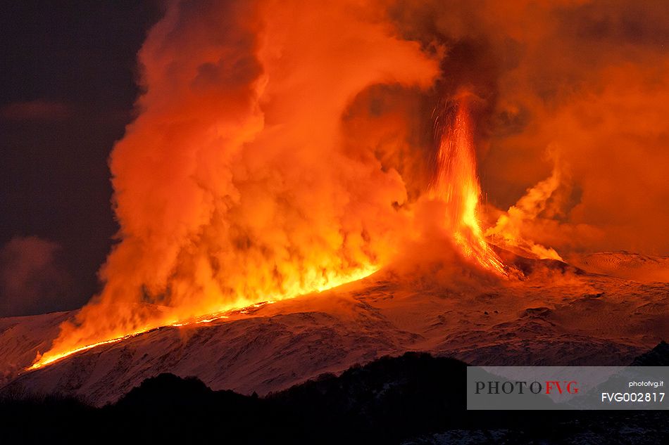 Etna 2nd paroxysm activity of 2012, a lava flow meets snow forming huge clouds of vapor illuminated in red.