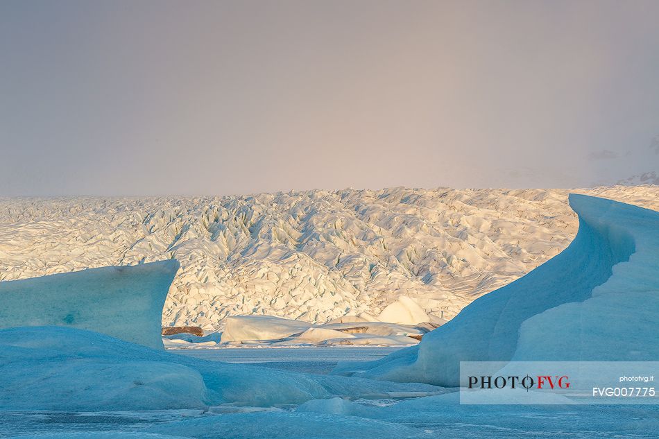 Iceberg on lagoon and sunlight on glacier in backgroud