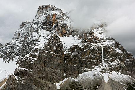 Mount Pelmo, after an abundant spring snowfall. Surrounded by threatening clouds, it releases the load of its snow into frequent and noisy avalanches, Zoldana valley, dolomites, Italy