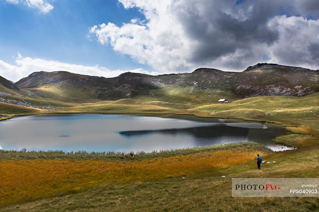 Hiker admires the quiet water of Fosses lake in the dolomites, Cortina d'Ampezzo, Veneto, Italy