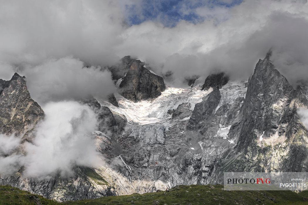 Les Grandes Jorasses partially hidden by clouds, from the grassy hill at the entrance to the Vallon de Malatr, val ferret, Courmayeur, Aosta valley, Italy, Europe