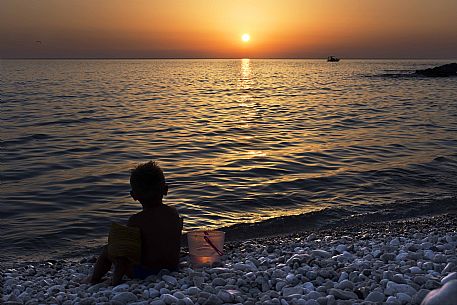 Child in backlight at sunset on the Macari beach, San Vito Lo Capo, Trapani, Sicily, Italy, Europe