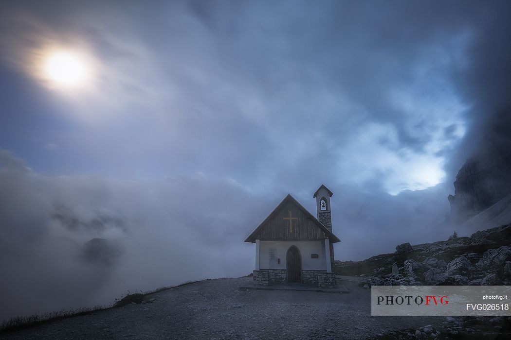 Alpine church wrapped by clouds at dusk, Tre Cime natural park, dolomites, Italy