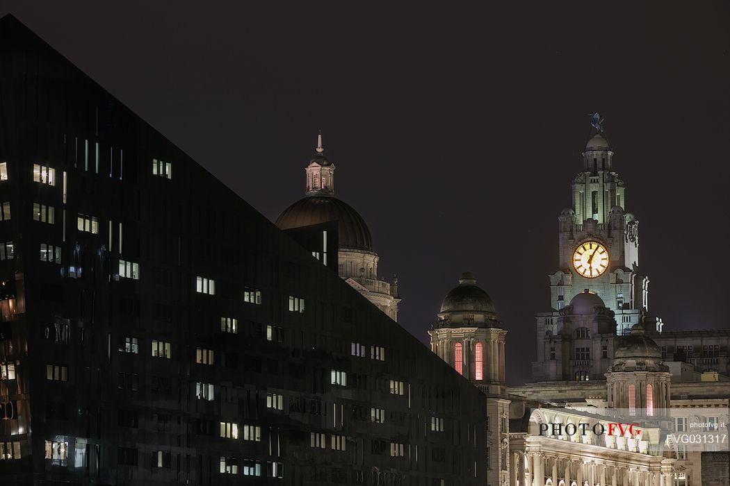 Cityscape from Albert docks at night, in the background the  Three Graces and the Royal Liver Building,  Liverpool, United kingdom